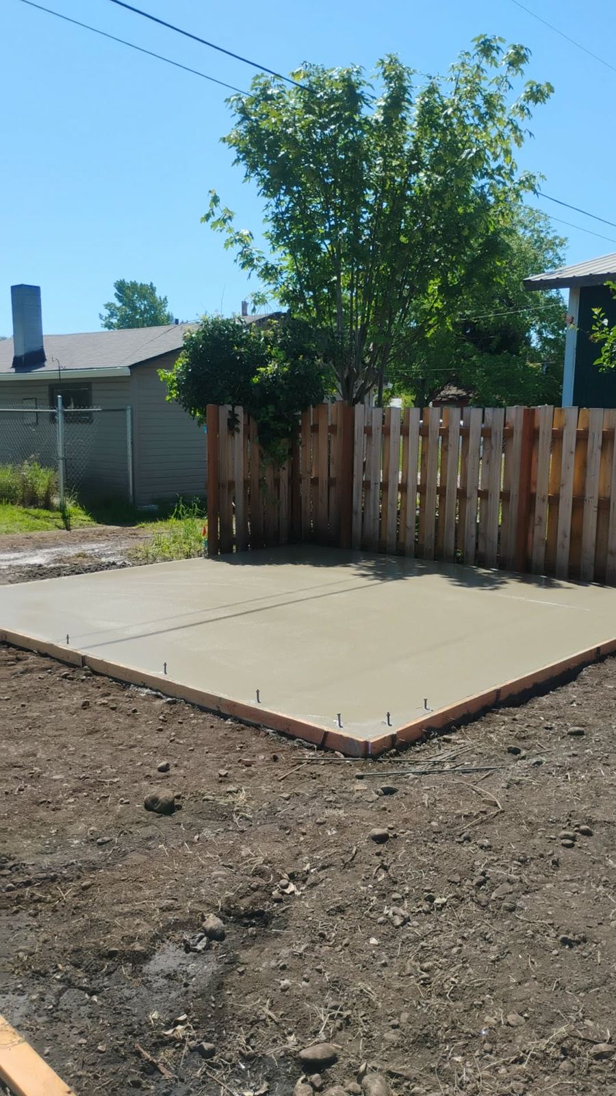 Backyard concrete patio by a fence