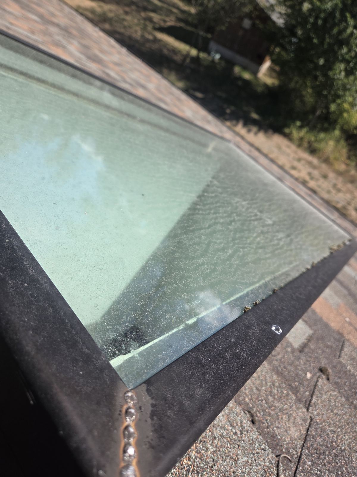 Skylight glass before cleaning, hazy with water spots and grime