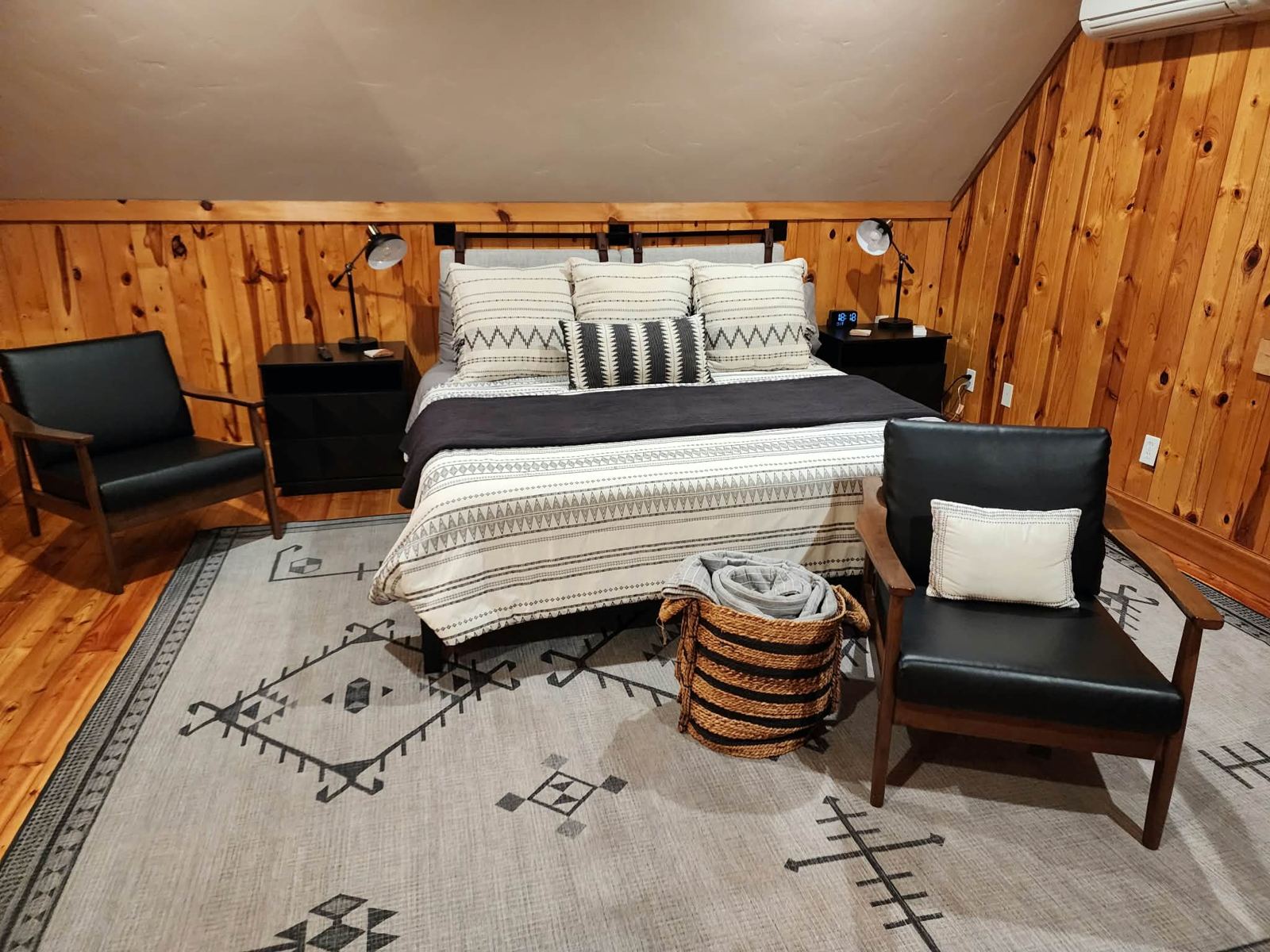 Loft bedroom with wood walls and two leather chairs